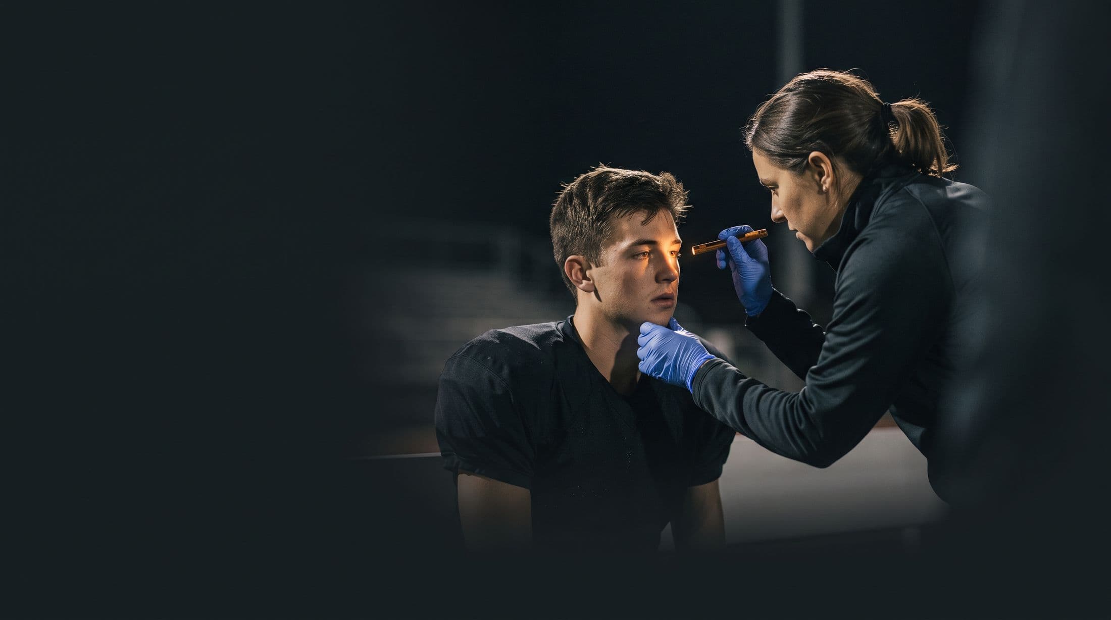Una profesional de la salud revisa con una linterna las pupilas de un atleta.